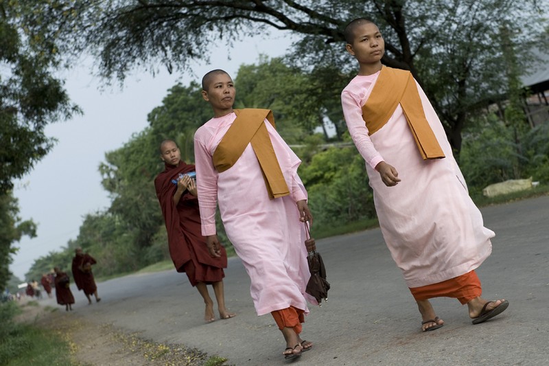 Две буддийские монахини идут по дороге на рассвете в городе Мандалай