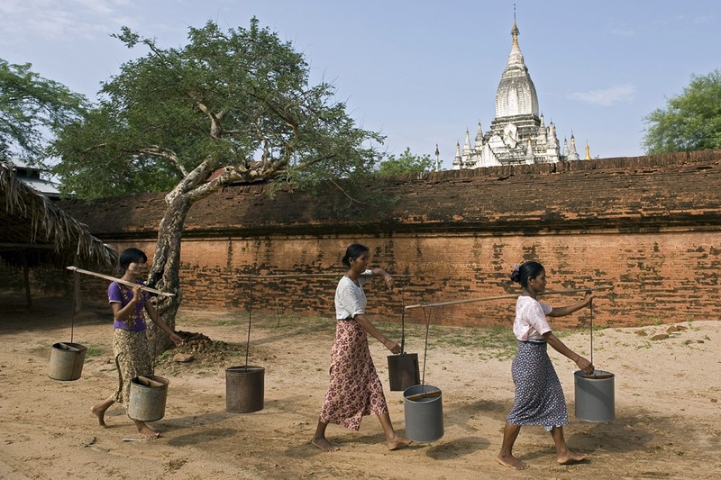 Местная женщина несет воду в городе Баган