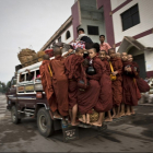 Буддийские послушники на задней части автобуса едут собирать милостыню на рассвете