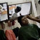 Мужчину стригут и бреют в парикмахерской в Янгоне
