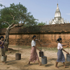 Местная женщина несет воду в городе Баган