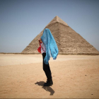Турист на солнце на фоне пирамиды Хефрена в Гизе. Туризм только возвращается в побитую демонстрациями страну. (Photo by Peter Ma