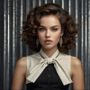 Image is a high-fashion portrait featuring a woman with voluminous, curly brown hair styled dramatically.