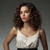 Image is a high-fashion portrait featuring a woman with voluminous, curly brown hair styled dramatically.