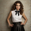 Image is a high-fashion portrait featuring a woman with voluminous, curly brown hair styled dramatically.